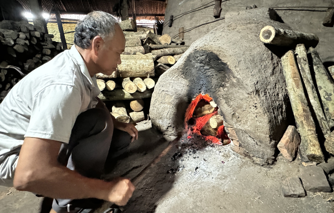Ông Hồ Văn Cao đang chăm củi vào lò hầm than của gia đình tại xã Xuân Hòa, huyện Kế Sách. Ảnh: An Bình