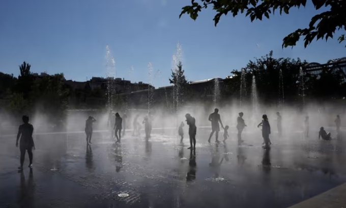 Người dân giải nhiệt bên dưới đài phun nước ở công viên Madrid Rio tại Madrid, Tây Ban Nha, hôm 23/7. Ảnh: AFP